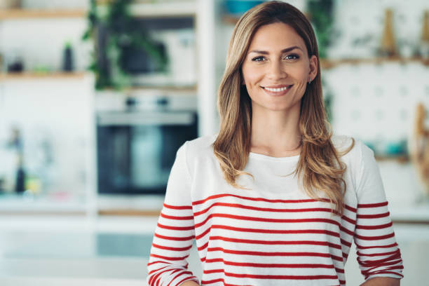 istock Smiling young woman standing in the kitchen 2023305329