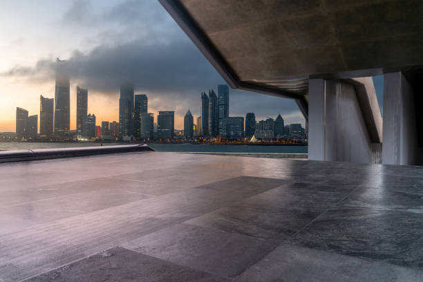 mpty concrete square with modern cityscape during sunrise. copy space for parking lot.