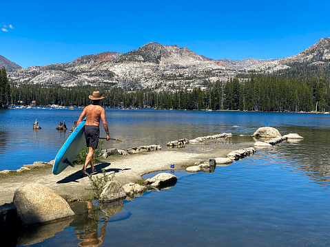 Man carrying paddle board. Wrights lake, California