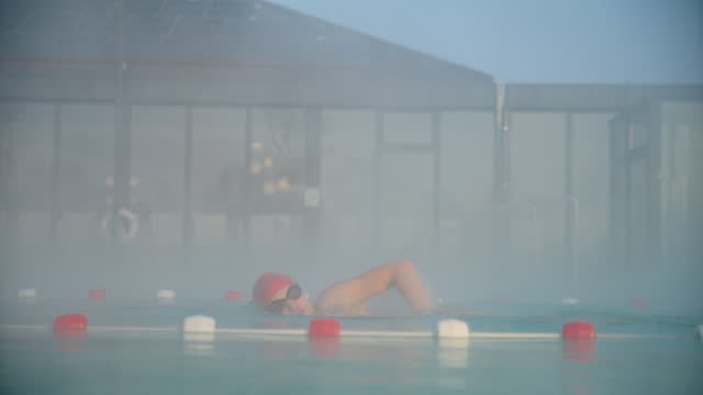SLO MO Determined Female Swimmer Practicing Freestyle Stroke in Foggy Pool during Dawn at Luxury Tourist Resort