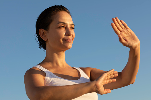 Female is doing tai chi with clear sky in background