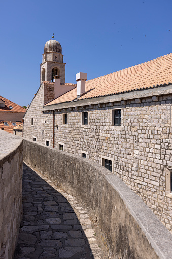Dubrovnik, Croatia - June 27, 2023: View of City Walls with Clock tower, surrounding medieval city on the Adriatic Sea. The Old Town with historical center is known as the pearl of Dalmatia