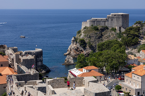 Dubrovnik, Croatia - June 27, 2023: Tourist walking route around the City Walls surrounding the medieval city by Adriatic Sea. Fort Lovrijenac in a dinstance