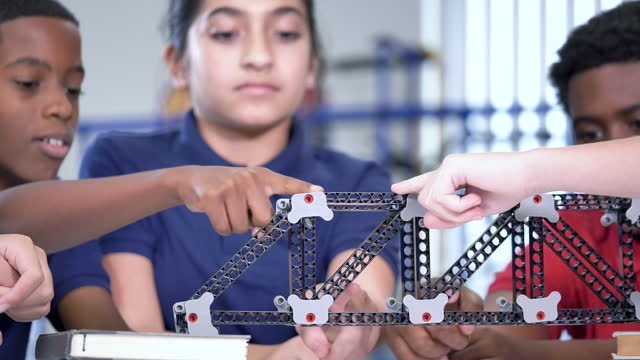 Middle school students in class examining model bridge