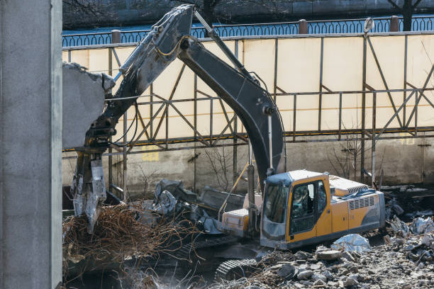 nettoyage des débris de construction avec un godet d’une excavatrice, l’excavatrice charge les restes du bâtiment détruit dans la voiture - demolition derby photos et images de collection