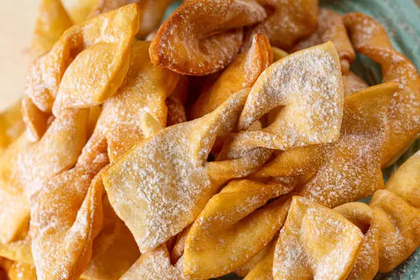 Close up of Angel wings or bugnes, bugie, or chvorost; faworki. Traditional sweet crisp pastry deep-fried and sprinkled with powdered sugar.