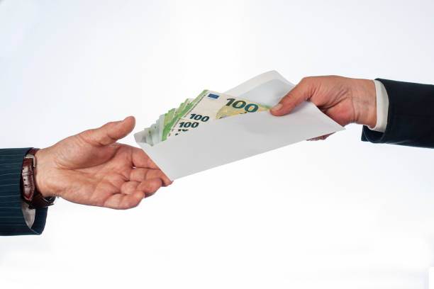 One hand passes an envelope of money to another hand