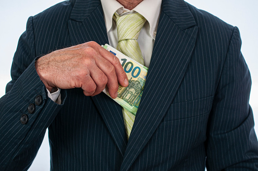 A businessman puts money inside his jacket
