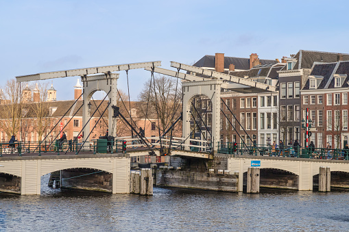 Amsterdam, Netherlands - April 4, 2019: Colorful houses, canal, tourists and tour boat of Amsterdam