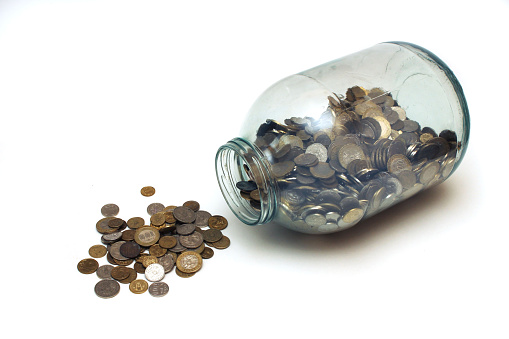 money poured from a glass jar on a white background