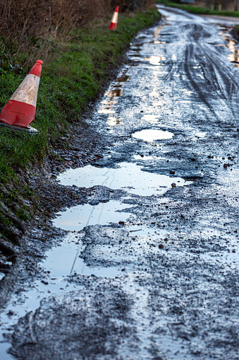 Pot holes filled with rain water causing a hazard on a country road in Sussex