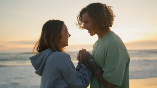 Happy sweethearts holding hands at sunset beach closeup. Man woman romantic date
