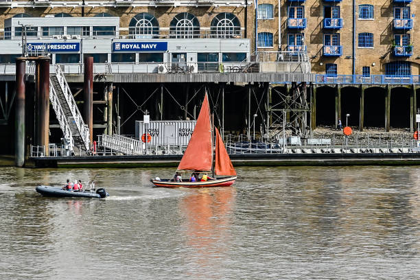 Ships And Boats Anchored On The River Thames In Front Of Modern Office Buildings In The City Of London, United Kingdom