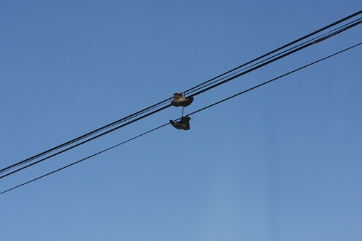 Boots dangling on power lines, capturing urban essence with an unexpected twist. A touch of rebellion in the cityscape.