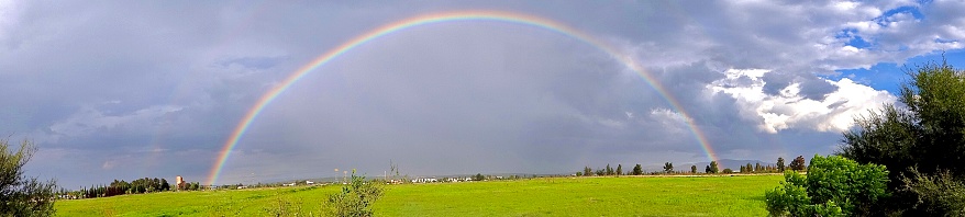 As an aeroplane approaches Christchurch airport in New Zealand, a rainbow can be seen out of the window.