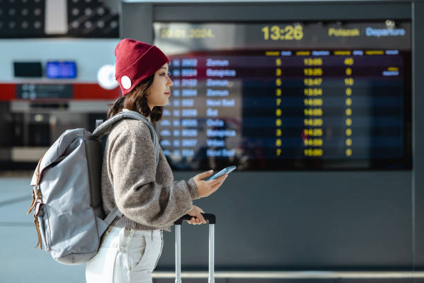 istock Smiling Chinese woman using mobile phone at the airport 2023654030