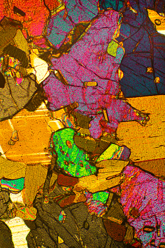 Abstract micrograph of a thin section of the mineral orthopyroxenite, made with a polarizing microscope at 40x.