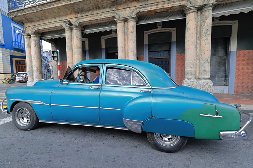 Havana, Cuba-October 07, 2019: Blue and green old American classic car -almendron, yank tank- Chevrolet Deluxe 4 door Sedan from 1951 stops at a red light, Paseo del Prado and Neptuno Street corner.