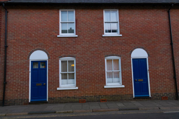 istock A red brick terraced house adorned with striking blue doors and white windows 2023699043