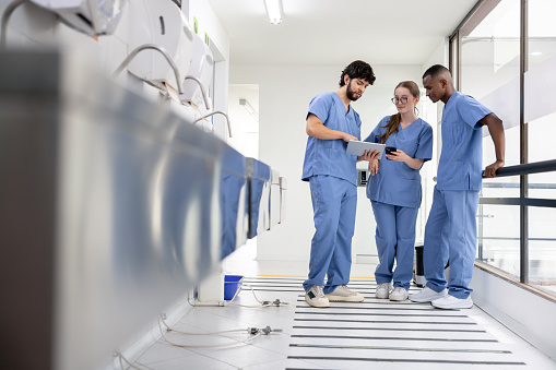 Group of medical students talking in the hall at the hospital and looking at a chart on a digital tablet