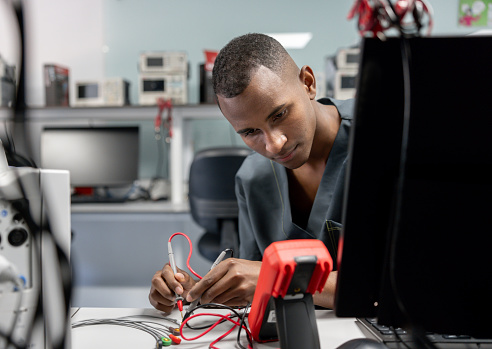 African American electrician repairing appliances using a multimeter