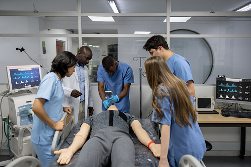 Team of medical students intubating a dummy at a teaching hospital - medical school concepts
