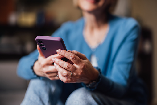 Close-up image of an older woman's hands holding a smartphone, symbolizing connectivity and modern lifestyle.