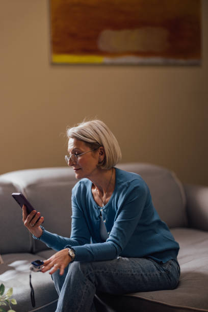 istock Senior Woman with Glasses Using Smartphone on Couch at Home 2023766451