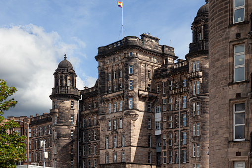 Part of the front facade of the Centre Block of Glasgow Royal Infirmary, a historic (1914) NHS hospital east of the city centre. An intersex-inclusive Pride flag is flying from the flagpole. Scotland, UK.It is a Category B Listed Building.