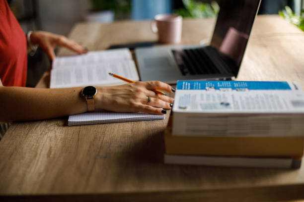 Close up shot of unrecognizable young female student studying and writing notes at her desk.