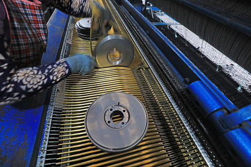 Workers replace shuttle cores at a fishing net processing plant, China