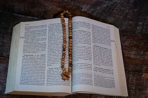 Small olive wood rosary on the open Bible, elements for prayer