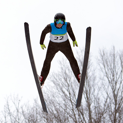 Low angle view of carefree woman having fun while skiing and splashing snow on a mountain. Copy space.