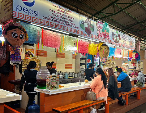 Oaxaca, Mexico: Customers sitting at a counter of a market stall selling tamales and other traditional foods in the famous Mercado Benito Juárez in downtown Oaxaca.