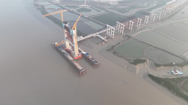 Aerial video of the under construction cross sea bridge construction site at sunrise