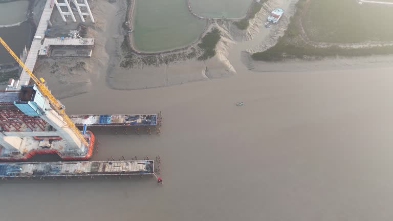 Aerial video of the under construction cross sea bridge construction site at sunrise