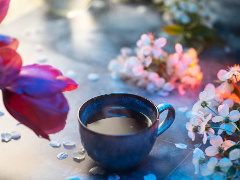 Morning cup of coffee on the table with a bouquet of tulips and cherry blossoms