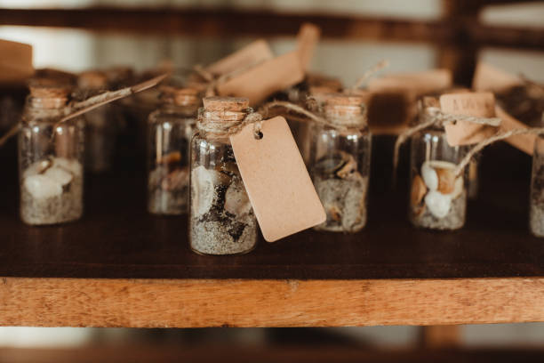 Charming display of dried herbs and botanicals in glass jars on a wooden shelf. Elements of nature captured with a rustic aesthetic, blending textures of glass, wood, and dried florals. Perfect capture of tranquility and vintage appeal in a cozy setting.
