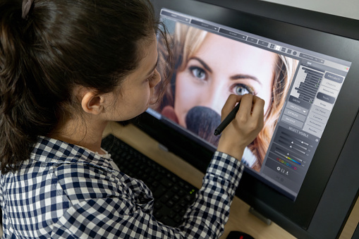 College student retouching a photo in an editing class using a computer and a stylus pen - IT education concepts