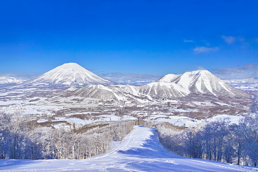 View of Mt. Yotei and Rusutsu Ski Resort from inside the slopes of Rusutsu Ski Resort in Hokkaido, Japan on a clear day in the middle of winter