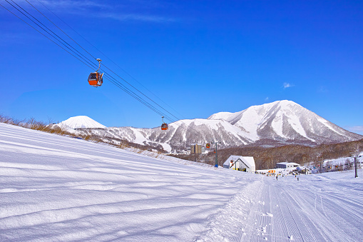 Sunny midwinter scenery of Rusutsu Ski Resort in Hokkaido, Japan, with gondola lift and Mt. Yotei