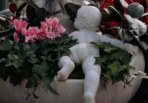 Baby sculpture in greenhouse with flowers and plants