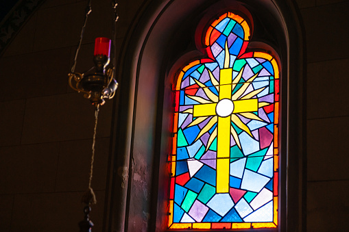 Window in the church, stained glass, colored mosaic in the form of a cross