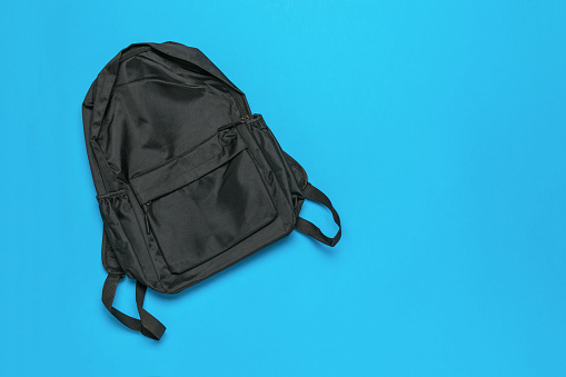 Black zippered backpack on a blue background. Universal shoulder bag.