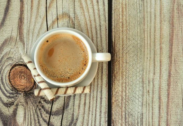 istock A cup of fresh cappuccino and two waffle rolls on a wooden table. 2024113528