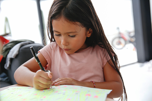 Close-up shot of multiracial little girl making a DIY greeting card for mother's day. Concept : kid's creativity, art, craft at home