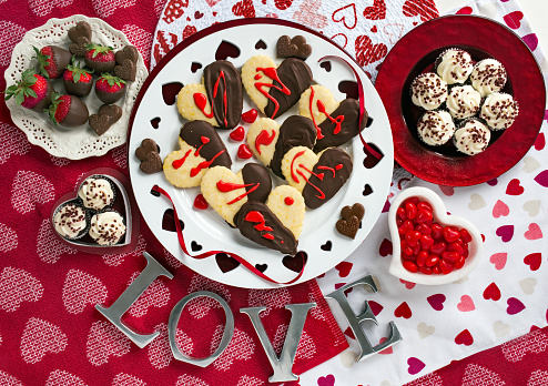 Dessert plates of frosted, mini cupcakes, chocolate-dipped cookies and strawberries and heart candies with the word 'love'.