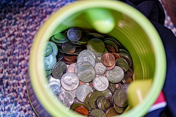 Looking down from directly above into a container holding hundreds of United States coins, with many different dates. The collection includes pennies, nickels, dimes, quarters, half dollars and dollar coins.
