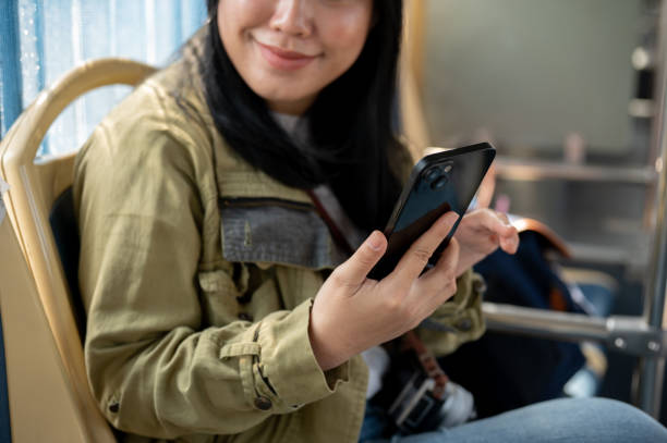 istock A smiling Asian female passenger is using her smartphone while sitting in a bus. 2024263158