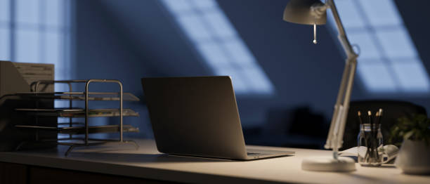 istock A modern dark home office at night with a laptop computer, a table lamp, and decor on the table. 2024275566